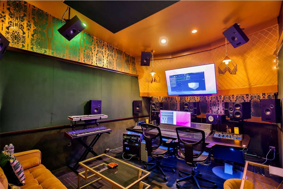 A modern recording studio with a mix of analogue and digital equipment, including Dolby Atmos Mixing in a high end environment, PMC speakers, and spatial audio mixing.