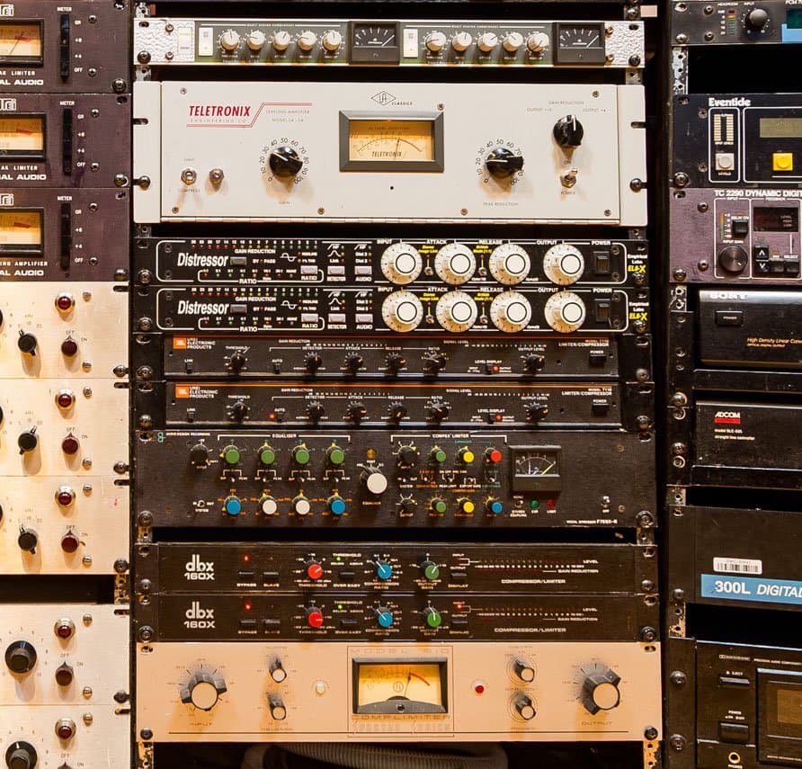 A rack of audio equipment featuring compressors, equalizers, and other sound-processing units. ADR Vocal Stressor, Distressors, LA2A, Allen Smart C2 compressor